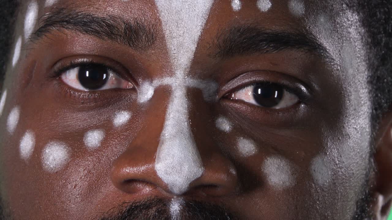 rostro de un hombre afroamericano con un patrón étnico blanco. hombre negro mirando hacia adelante y sonriendo. pantalla verde, llave de croma. ojos cerrados, retrato macro