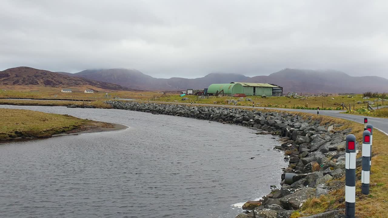 Rural Landscape with River, Road, and Mountains under Cloudy Sky