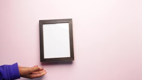 person holding an empty black picture frame