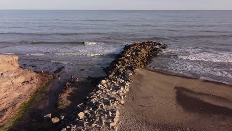 aerial orbit shot family at beach enjoying beautiful south atlantic ocean with breakwater during sunset in argentina