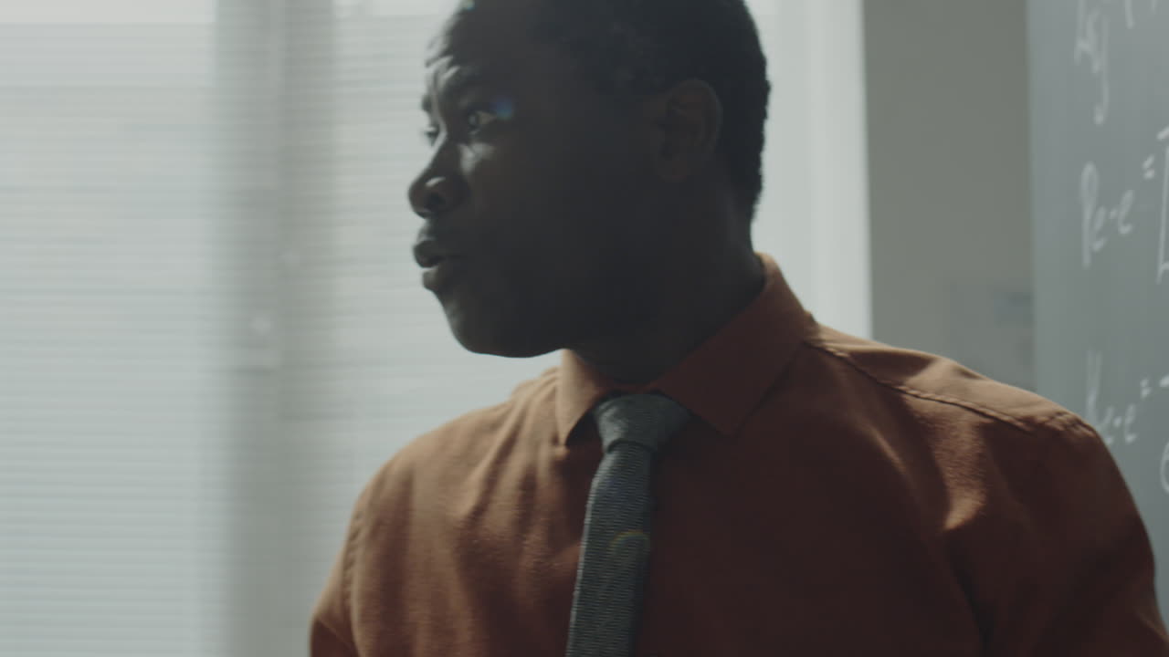 A professor explaining concepts on a blackboard with scientific formulas