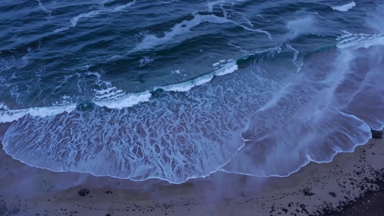 Il video aereo cattura una costa serena con onde delicate che lambiscono la riva