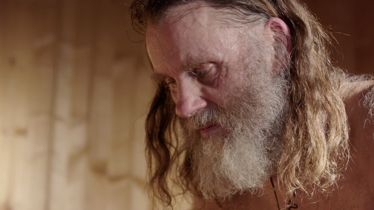 Ungroomed Nordic man sits in hot sauna doing mindful reflection meditation