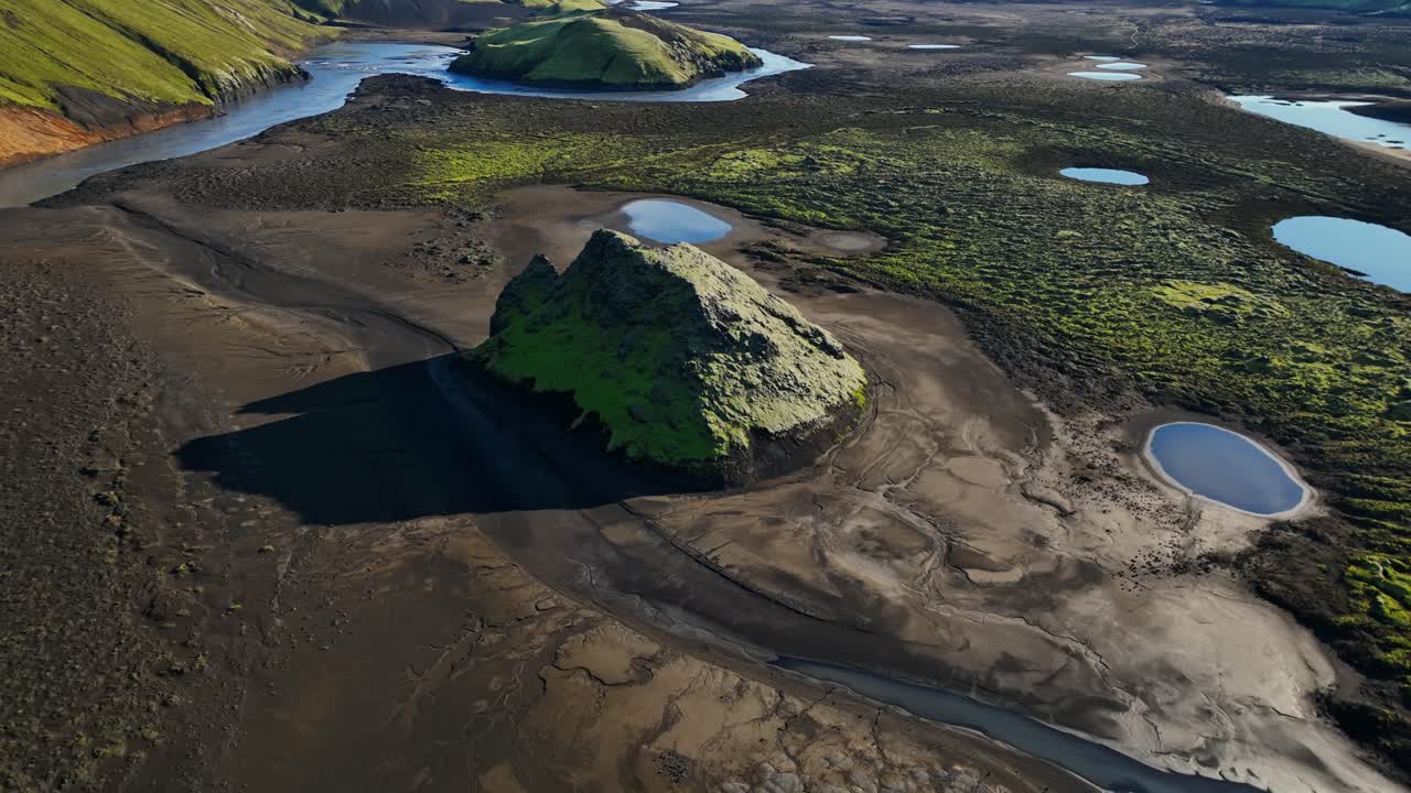 Vista aerea da drone sul delta del fiume negli altopiani islandesi con pianure di sabbia nera, colline muschiose e lagune sparse, vasta area vulcanica selvaggia sotto un cielo azzurro sereno