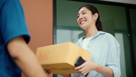 young woman signing electronic signature on smartphone for agreement of contract digital receiving parcel from blue delivery man from shopping online. courier man delivering package to destination.