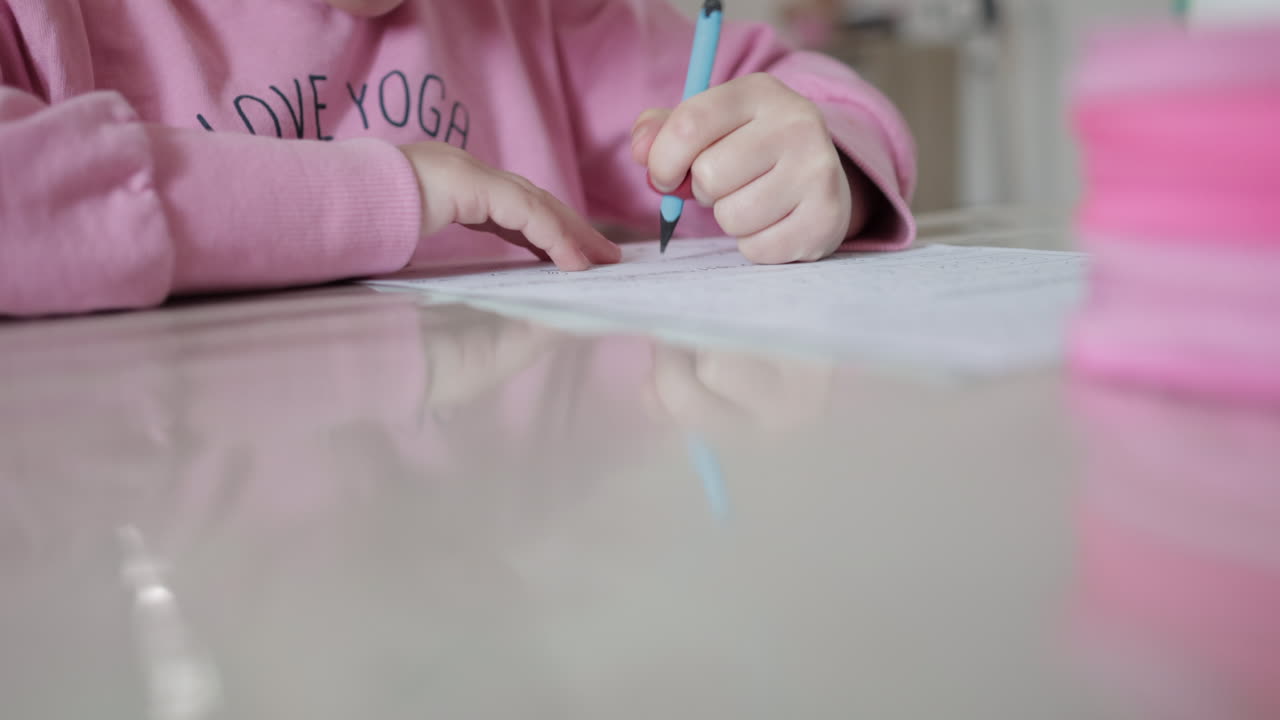 Homework time — child’s hand writing on paper. front view