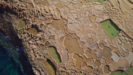 Dynamic-Aerial-Over-Salt-Pans-on-Coast-of-Gozo-Island,-Malta