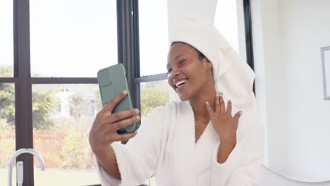 mujer biracial feliz con parches debajo de los ojos tomando una selfie con un teléfono inteligente, cámara lenta