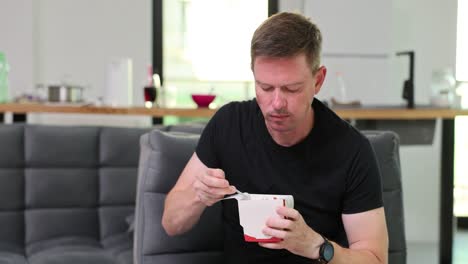 Man Eating Takeout Food on Sofa at Home