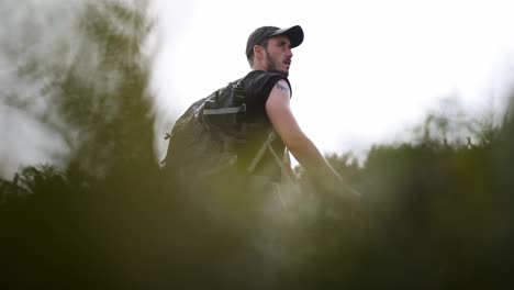 adventure man walking next to a cliff between the branches, close up shot