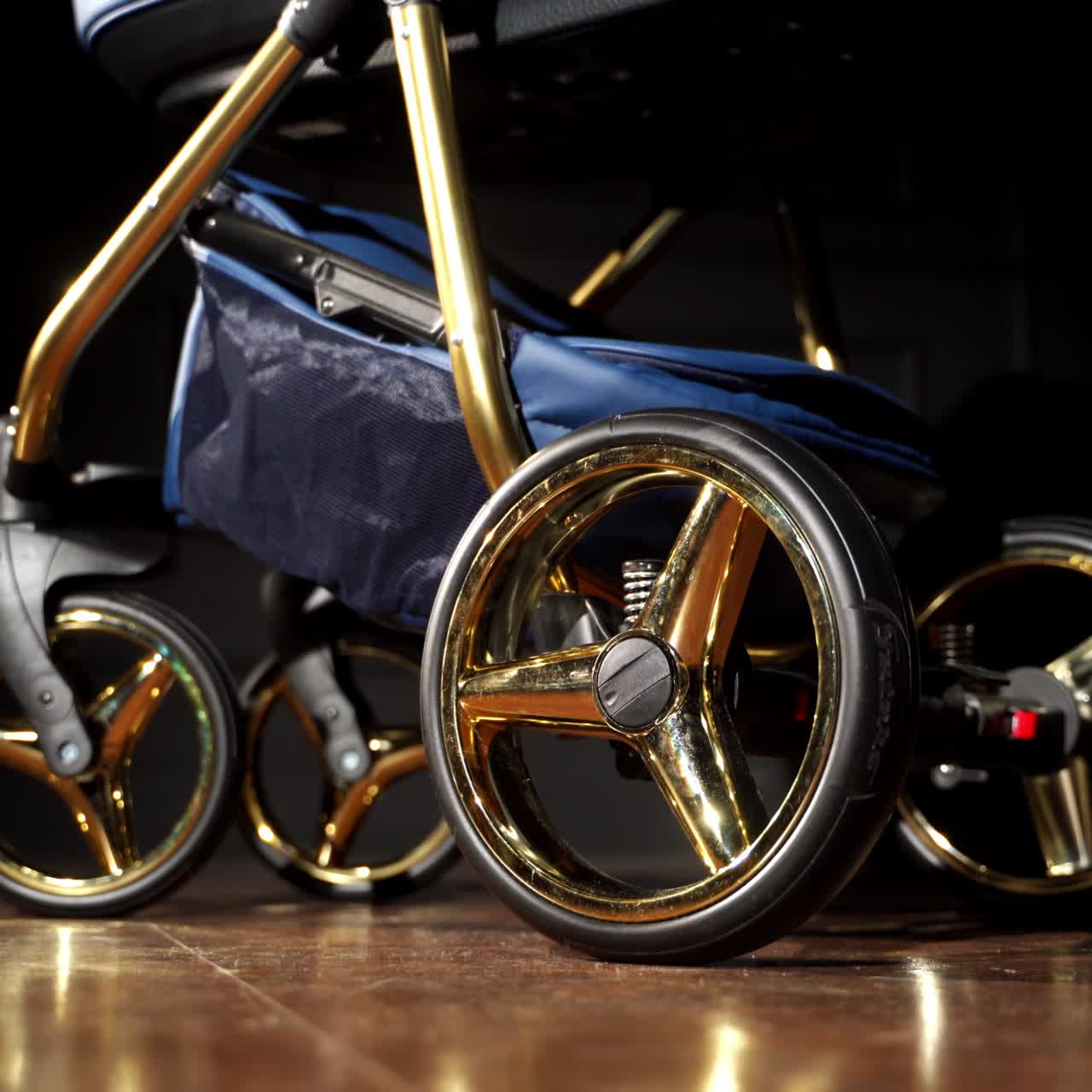 Nice modern baby stroller with shining golden elements in wheels. Baby pram being shaken in the dark room