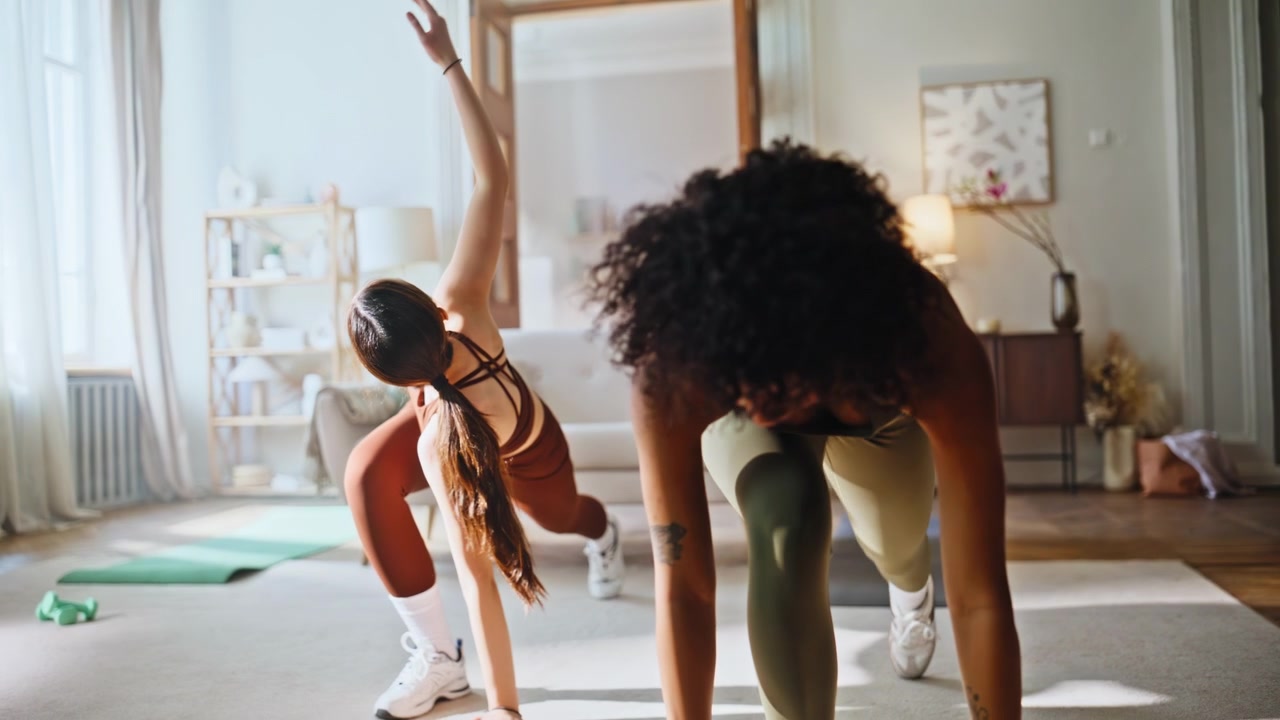 Sporty women stretching together home. Side lunge fitness workout morning.