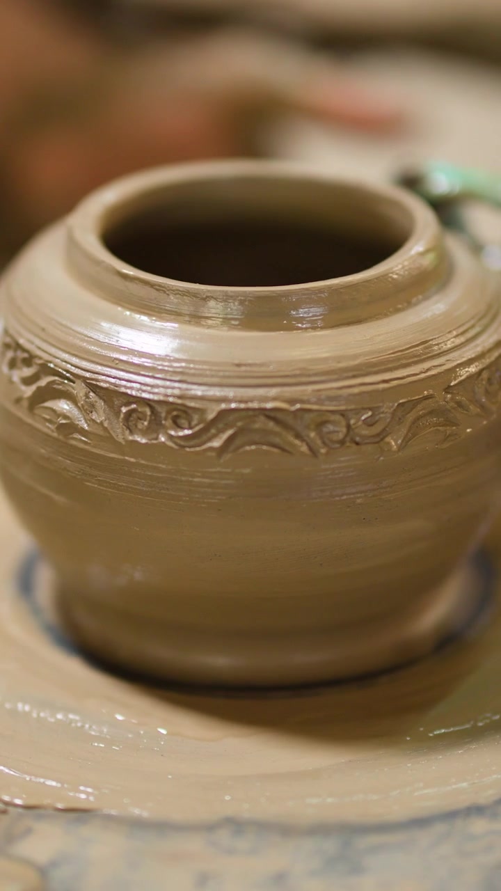 Un vaso di argilla bagnato con motivi ornamentali gira su un tornio da vasaio a Nonthaburi, Thailandia