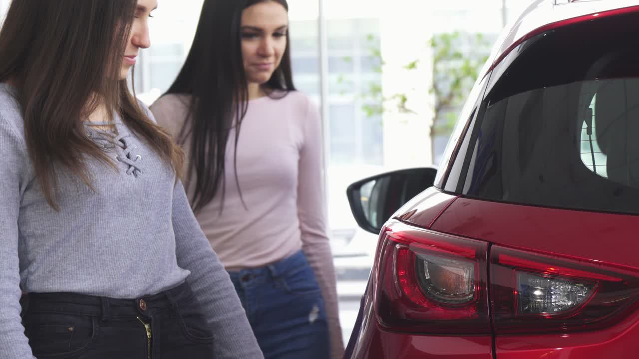 fotografía recortada de dos mujeres eligiendo coches en el concesionario