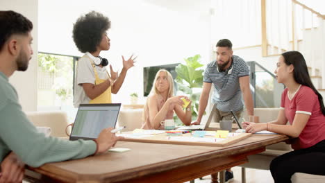 young diverse friends brainstorming ideas around table with laptop and sticky notes