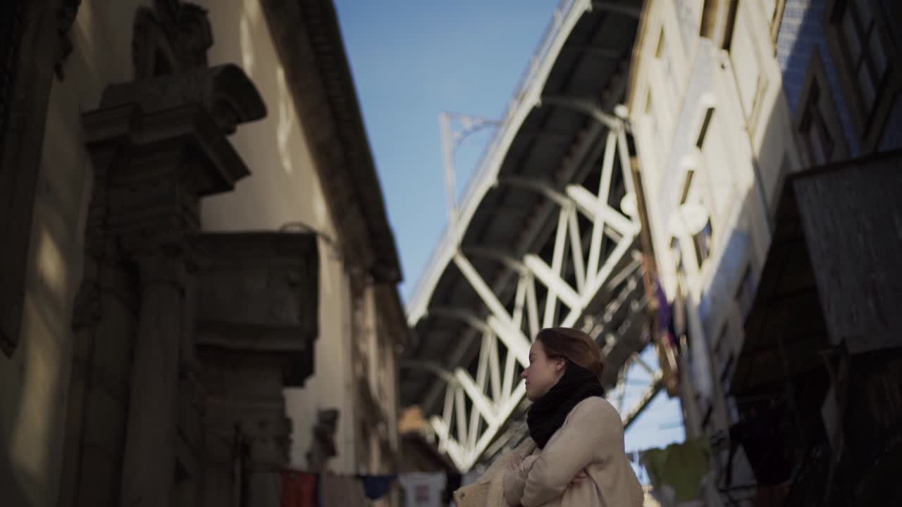 Giovane ragazza bruna in posa davanti a un famoso ponte a Porto in una giornata di sole
