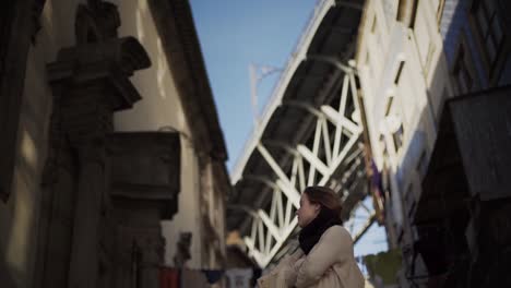 Young-brunette-girl-posing-in-front-of-famous-bridge-in-Porto-during-sunny-day