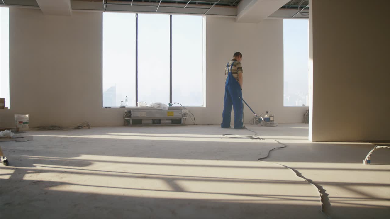 건설 노동자 가 사무실 공간 에서 새로운 바닥 을 고 있다