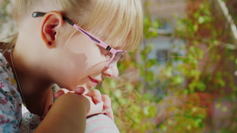 una niña de 6 años con gafas de sol mira por la ventana 2