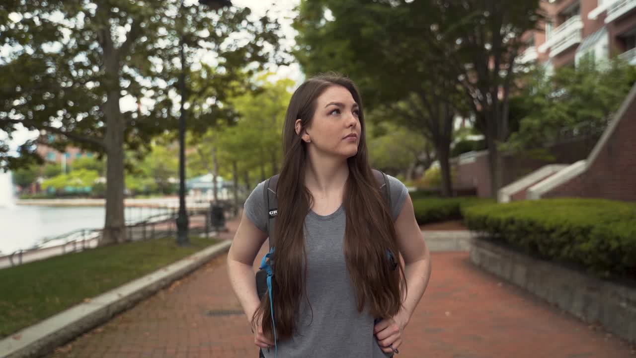 estudiante universitaria caminando por el cuadrilátero de la universidad explorando el campus sola, a mitad de camino en cámara lenta