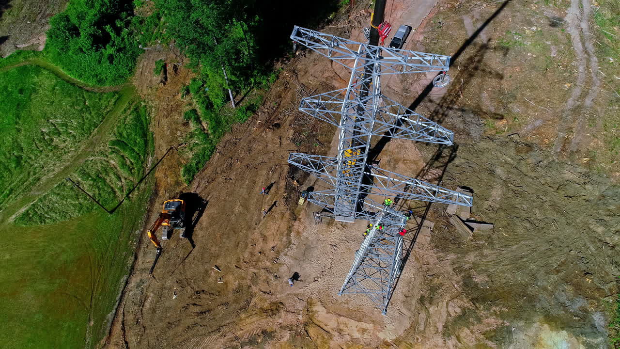 Group of industrial worker installing new transmission tower in rural area during sunlight