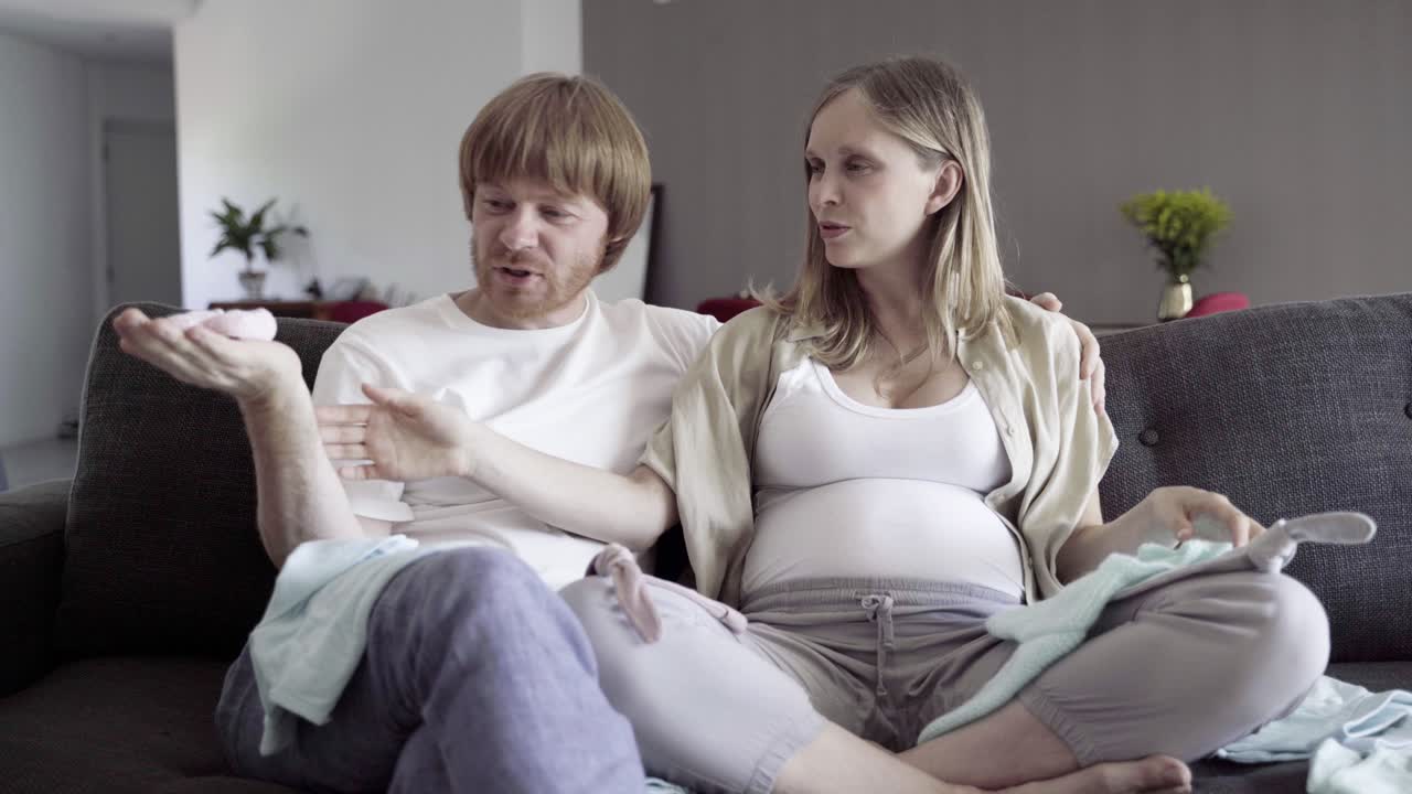 행복한 젊은 부부가 아이를 위한 옷을 찾고 있습니다.