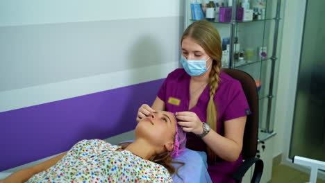 cosmetologists putting cosmetology hat on client before examining facial skin of a female. woman face being checked by beautician. video from the top.