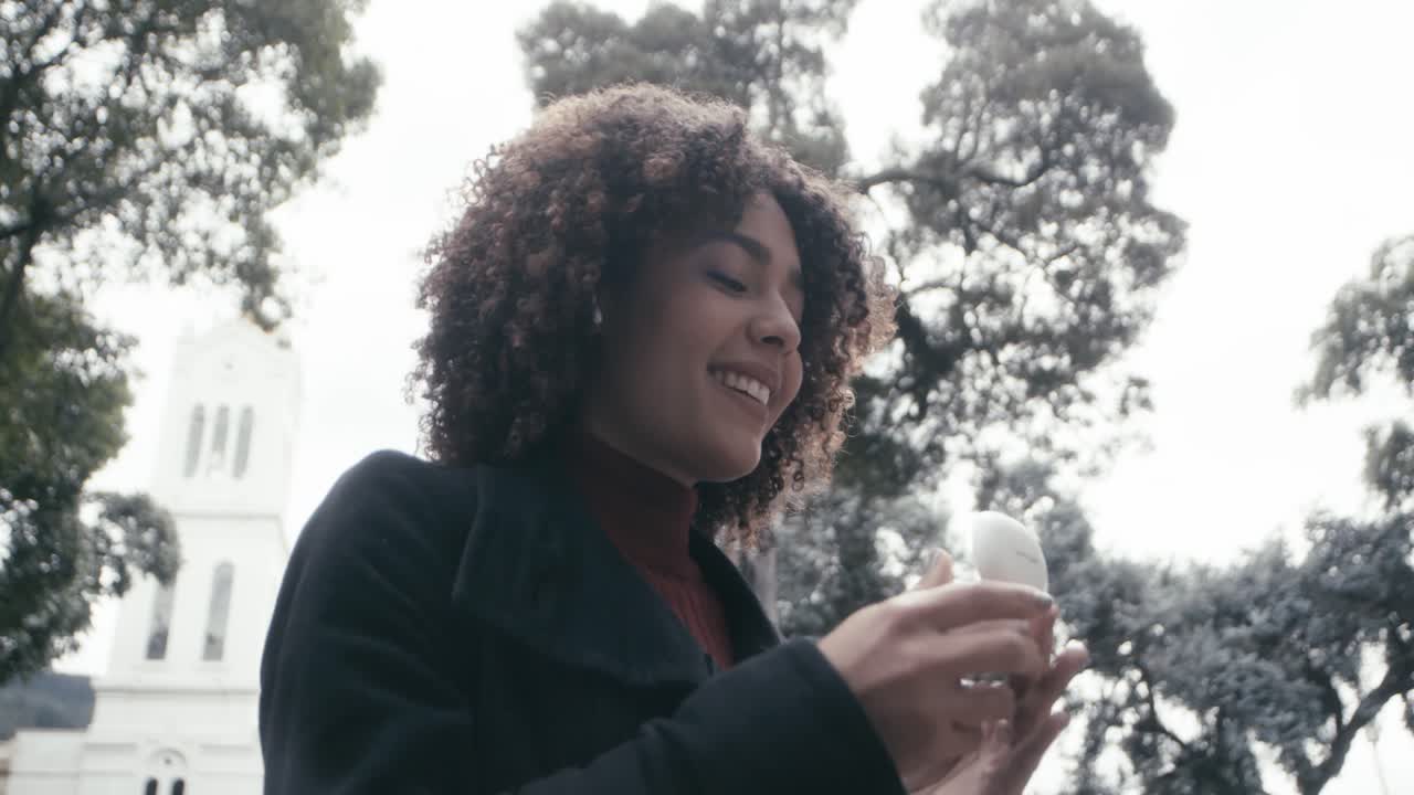 Ragazza con i capelli ricci cammina per la città di Bogotà mentre indossa gli auricolari, Colombia.