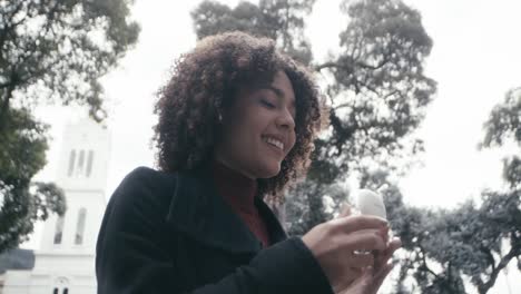 curly hair girl walks around the city of bogota while wearing earbuds, colombia