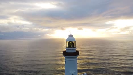 drone aerial view of the sunrise behind the famous lighthouse of byron bay, australia