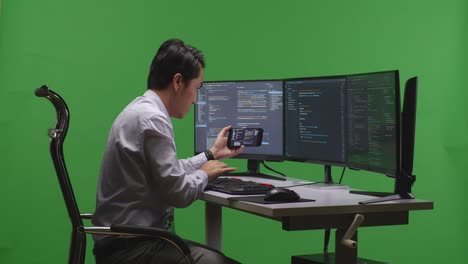 그린 스크린에서 책상에서 일하는 프로그래머