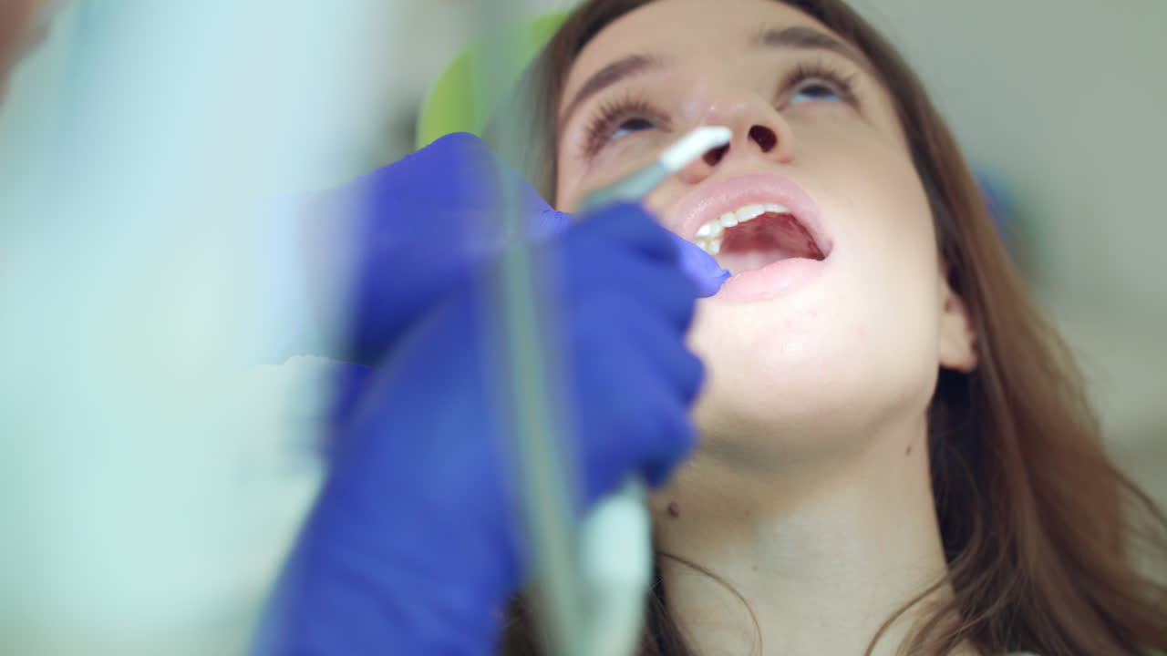 Woman treating teeth at family dentist. Dentist hands working at woman mouth