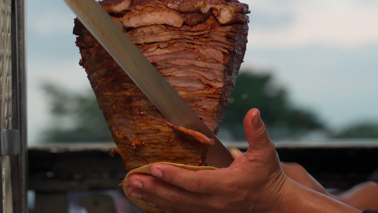 taquero cortando carne al pastor carne de cerdo cruda fresca auténtica de trompo kebab shawarma a la parrilla asada tortilla en la mano receta caliente latino mexicano