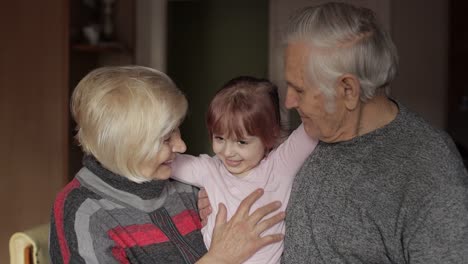 Smiling-family-grandfather,-grandmother-with-child-granddaughter-at-home