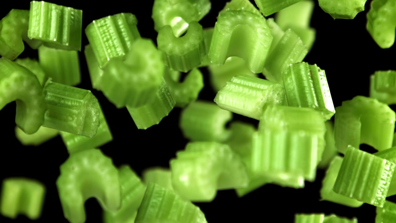 Chopped Fresh Celery Pieces Falling in Slow Motion on Black Background