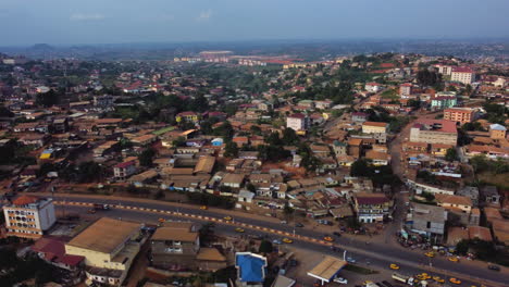 Aerial-view-of-traffic-and-African-homes-in-the-Emana-district-of-Yaounde,-Cameroon---tracking-drone-shot
