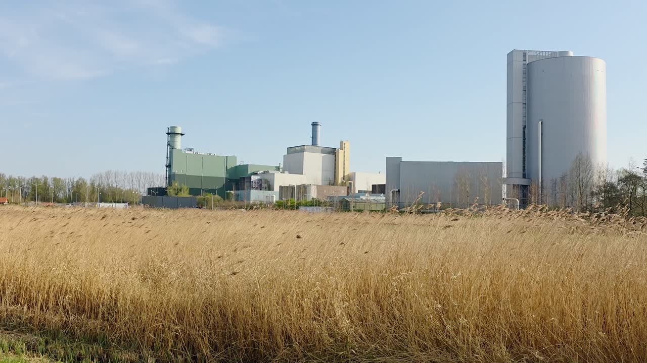Moving past a gas powered electricity factory and grass fields