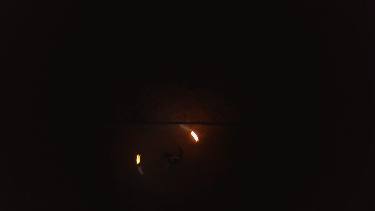 Young blond male does fire dance with two torches spins burning torches Drone view