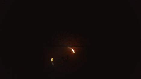 young blond male does fire dance with two torches spins burning torches drone view