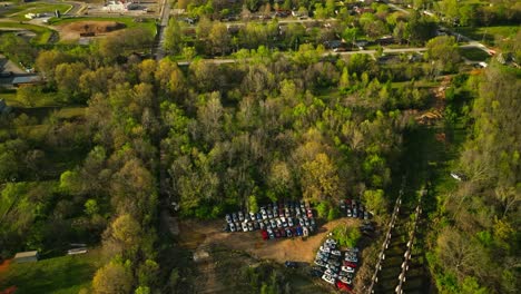 Aerial-view-of-junk-yard-in-with-stacks-of-used-cars-in-wooded-area-in-Fayetteville,-Arkansas,-USA