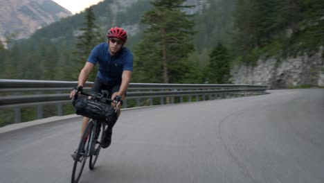 high speed chase, healthy man on a bicycle cycling through a mountain pass in the dolomites, italy