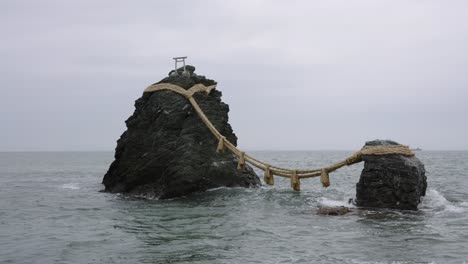 Meoto-Iwa-Rocks,-Futami,-Mie-Prefecture,-Japan,-Waves-Banging-on-Overcast-Day