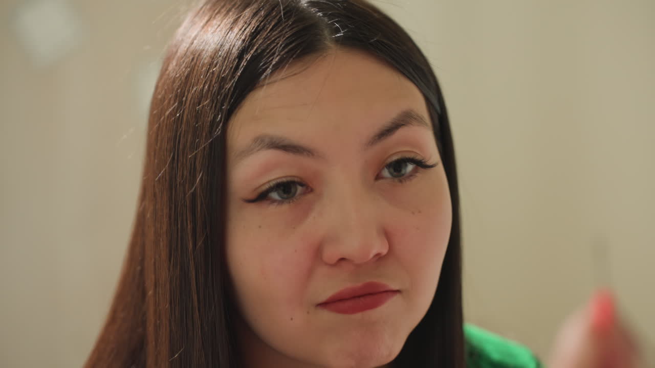 아시아 여성이 립스틱을 바르는 모습, 그루밍 도구를 활용한 뷰티 루틴을 보여주는 스튜디오 장면, 메이크업 아티스트가 전문적인 환경에서 집중된 표정으로 섬세하게 립스틱을 바르는 모습