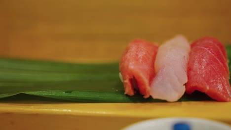 nigiri sushi on banana leaf, close pan of gourmet fish market restaurant