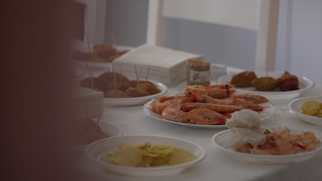 Buffet table with plates of shrimp, finger foods, and chips arranged neatly for an event
