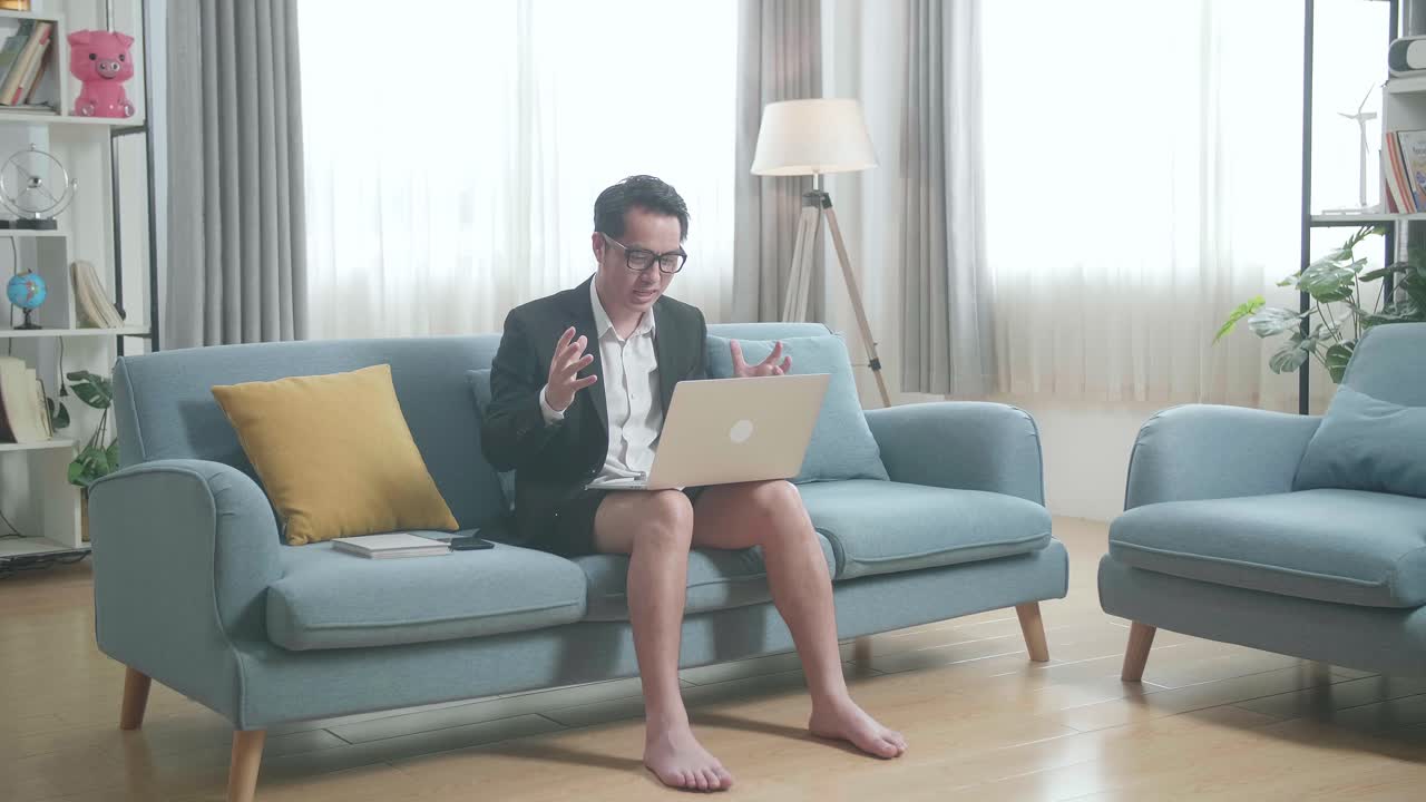 hombre en traje de negocios teniendo una llamada de video mientras está sentado en un sofá