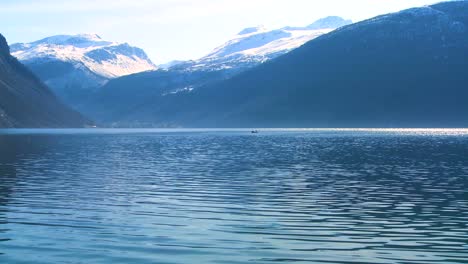 Beautiful-wide-shot-of-the-fjords-of-Norway-with-people-in-a-canoe-distant-1