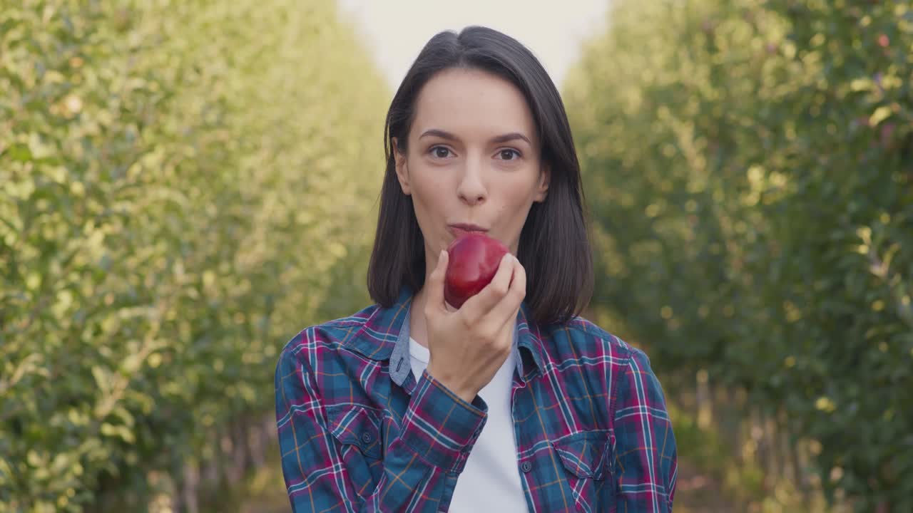 mujer comiendo una manzana en un huerto de manzanas