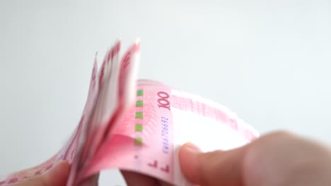 close up of female hands counting numbers of hundred rmb chinese paper money in white background