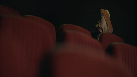 Man-sleeping-in-empty-cinema-hall.-Sleeping-man-feet-on-cinema-chair